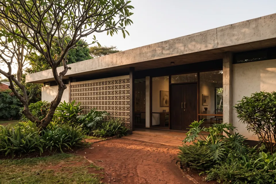 Umber House: a single-storey 1960s house with a deep concrete roof and a breeze-block screen, in a garden.